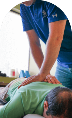 Man on chiropractic table with two hands on his back